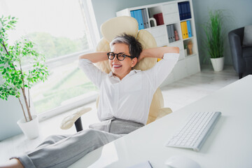 photo of cheerful nice old businesswoman hands head pause after google meet conference legs on desk 