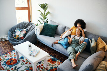 Wall Mural - Lesbian couple, relax and watching tv on couch, hug and comfort in home or living room, bonding and chilling. Happy cozy people, streaming a series or movie with remote for quality time, love and joy