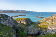 Blick über die Inseln von Sommarøy und Hillesøy mit Häuser, Brücke, Felsen, Wiesen und Strand, Ufer und Berg, Frau auf dem Berg in Norwegen. Panorama am sonnigen Herbsttag