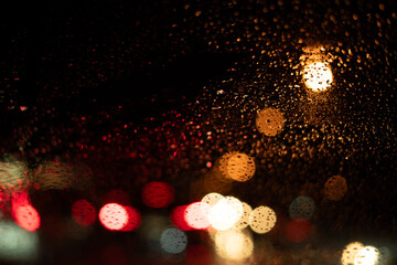 Wall Mural - Rain drops on the car glass with traffic light bokeh background.