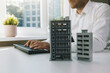 © ronstik - real estate business and development. businessman, developer or architect working in office, typing on computer keyboard. new apartment building scale models on the table