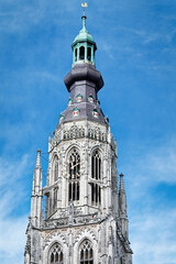 Wall Mural - the gothic church tower of the protestant onze-Lieve-Vrouwekerk in breda against a blue sky with clouds