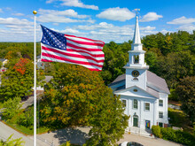 First Religious Society Church Aerial View At 27 School Street And US National Flag At Town Common In Historic Town Center Of Carlisle, Massachusetts MA, USA. 