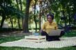 © kerkezz - a beautiful smiling young woman sitting in the park and working on a laptop