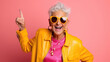Funny stylish elderly grandmother in glasses poses at studio. Senior old woman looking at camera over bright background.