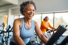 Middle Aged African American Woman On Stationary Exercise Bike At Gym, Maintaining A Healthy Lifestyle, Focused On Exercises