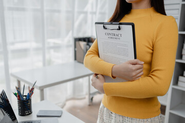 Young Asian business woman dialing a telephone, business woman working in finance, planning finances for a startup company and reviewing financial statements. Financial management concepts.