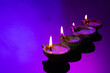 Close up of four diwali candles with copy space on purple background