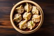Top view of bamboo steamer containing momo dumplings on wooden background