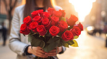 A young woman holds beautiful red roses in her hands