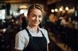 © Baba Images - Smiling portrait of a happy young female caucasian waitress working in a cafe or bar