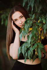 beautiful young woman posing in dark green foliage, girl face on summer nature, beauty and fashion concept