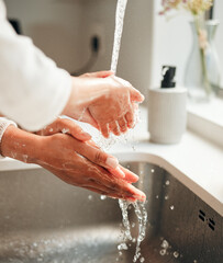  Closeup, hygiene and people washing hands in sink with water for cleaning, faucet or grooming. Zoom, sanitary and morning routine with soap, foam or liquid in basin for fresh fingers in a house