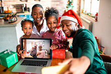 Young African American family at their home is taking a selfie with their grandparents that are on a video call on a laptop during the Christmas and new year holidays