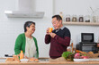 Happy Asian senior couple drinking fresh juice in the modern kitchen