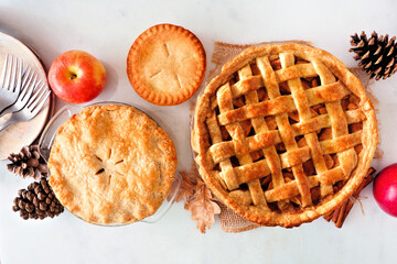 Poster - Variety of homemade autumn apple pies. Top view table scene over a white marble background.