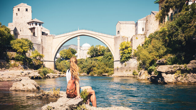 female tourist looking at famous old bridge and river of mostar- tour tourism,travel,vacation in bos