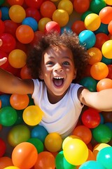  laughing child boy having fun in ball pit on birthday party in kids amusement park and indoor play center, laughing, playing with colorful balls in playground ball pool.