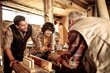 © Geber86 - Multigenerational family of male carpenters teaching their youngest one the ways in a carpentry shop