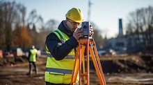 worker in a safety vest and hard hat is utilizing a surveying instrument to measure a construction