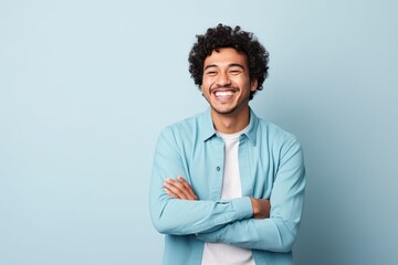 Wall Mural - A cheerful guy with a mop of curly hair and a vibrant blue shirt, beaming with infectious joy.