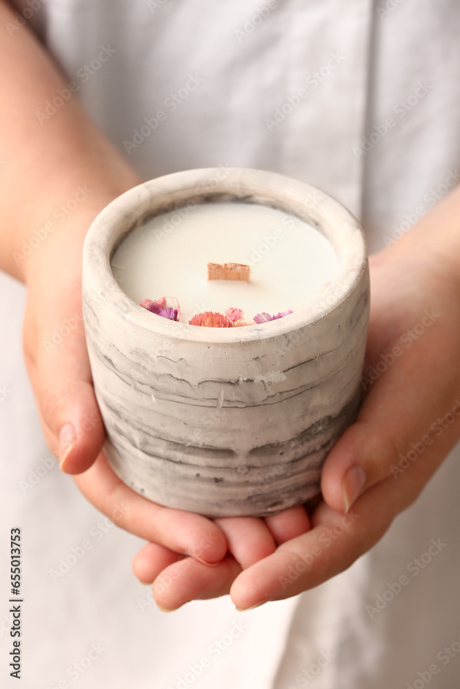 Woman holding candle with flowers, closeup