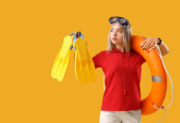 Wall Mural - Female lifeguard with ring buoy and flippers on yellow background