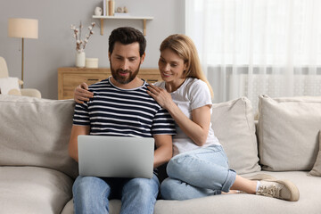 Canvas Print - Happy couple with laptop on sofa at home