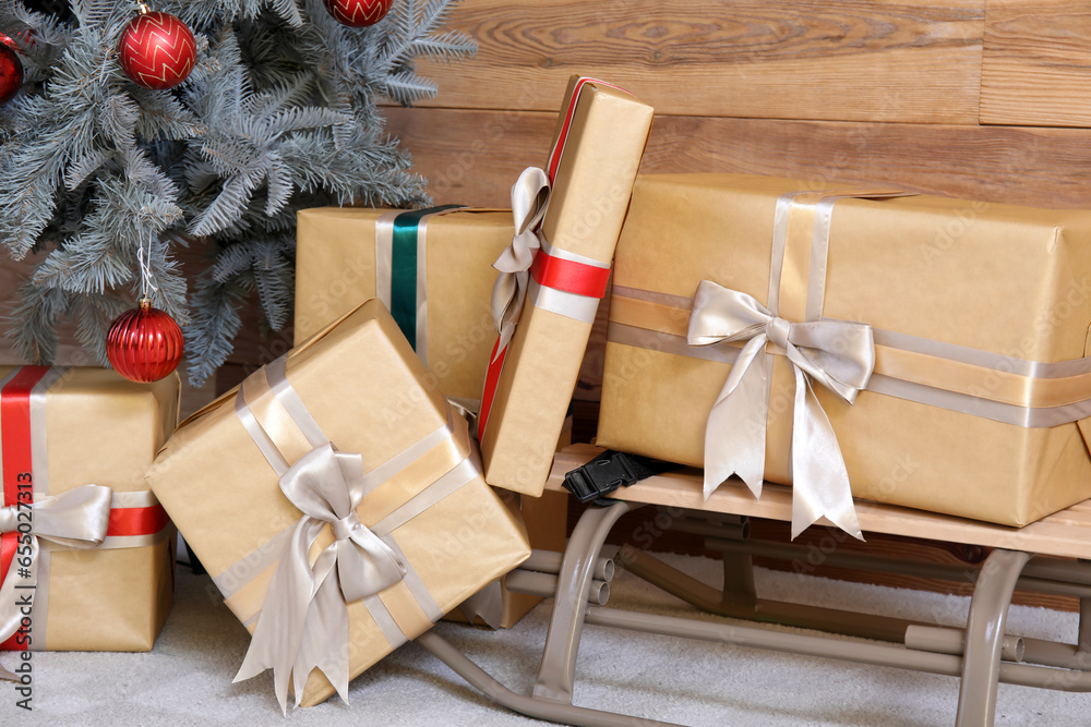 Christmas gift boxes with ribbons on sledge near Christmas tree