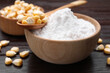 Bowl of corn starch and kernels on dark wooden table, closeup