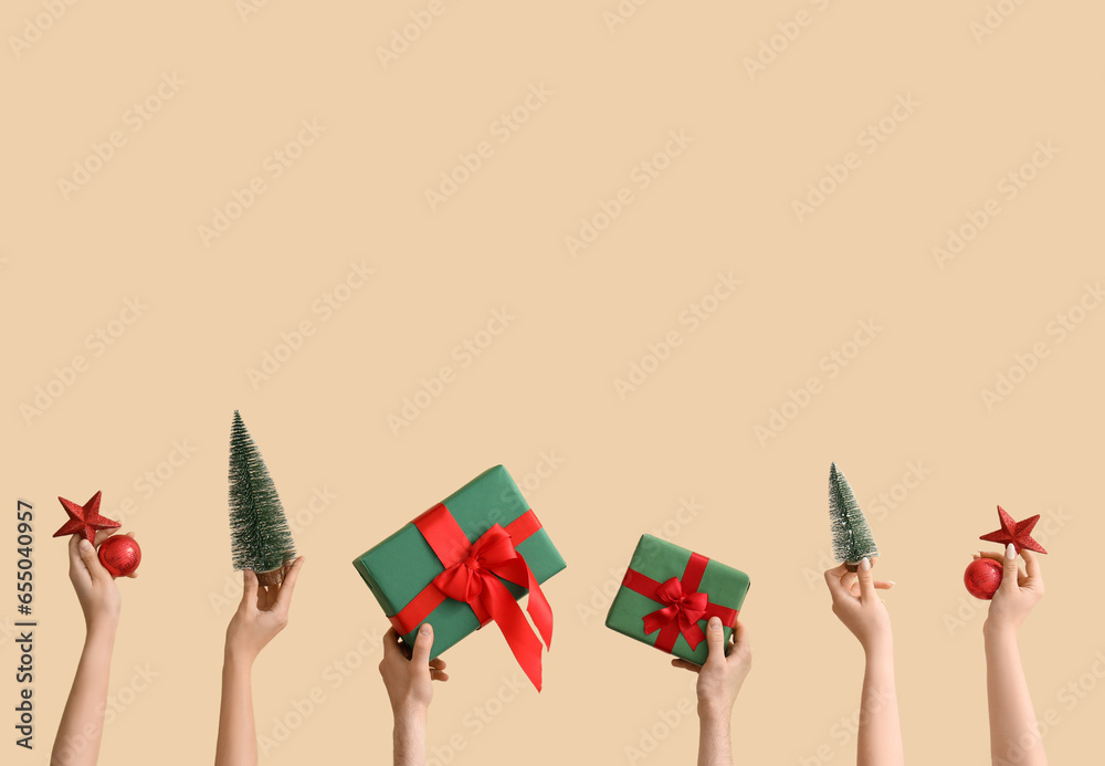 Hands holding Christmas gifts and decorations on beige background