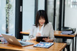 © Nuttapong punna - Successful Asian Businesswoman Analyzing Finance on Tablet and Laptop at Office Desk tax, report, accounting, statistics, and analytical research concept