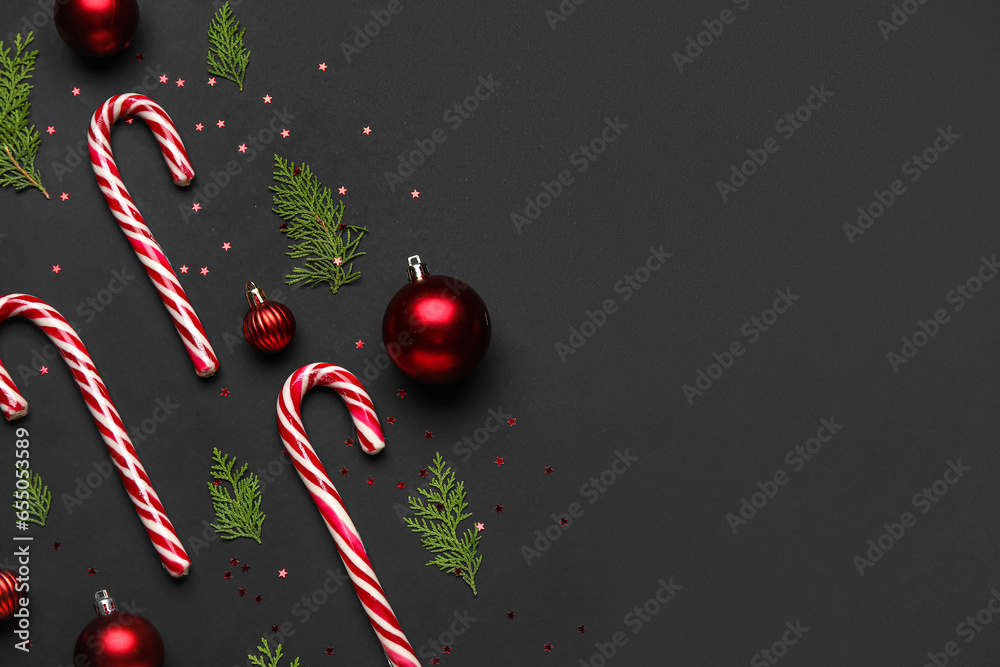 Composition with Christmas balls, thuja branches and candy canes on dark background