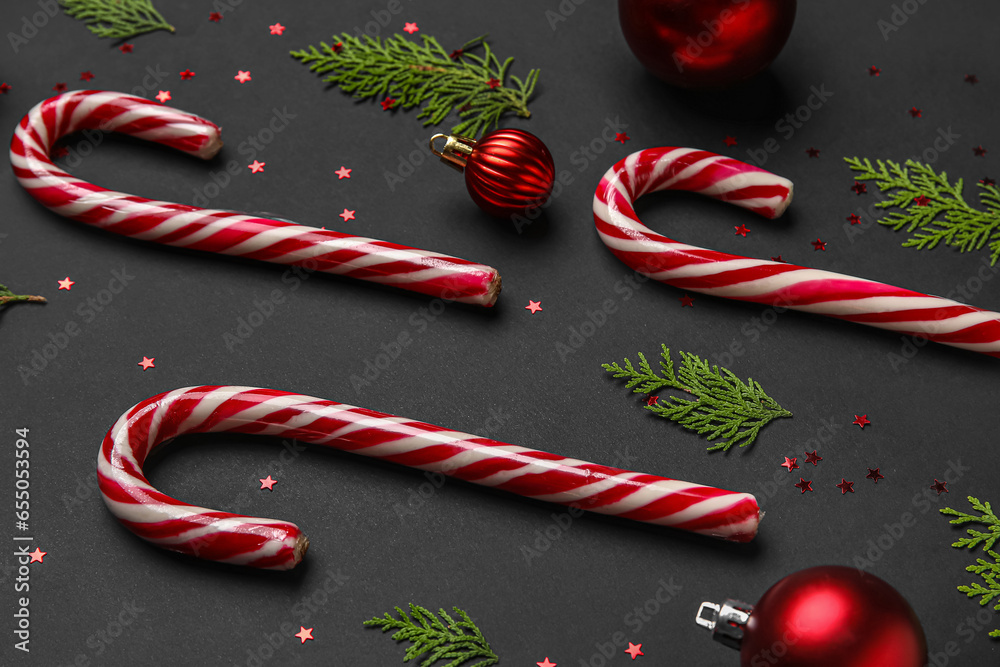 Composition with Christmas balls, thuja branches and candy canes on dark background