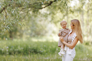 a young european woman in casual, comfortable beige clothes holding a small child in her arms in the