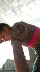 Wall Mural - An angle from the back shows a sporty young lady in athletic attire doing her warm-up routine on the urban streets.