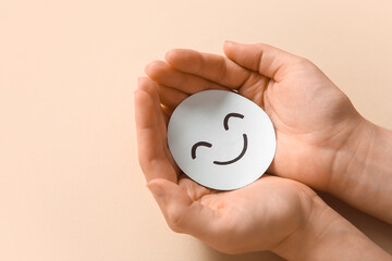 Wall Mural - Female hands with happy smile face on beige background. Mental Health Day