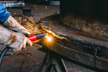 Wall Mural - Welder use carbon air arc gouging for hot work cutting or gouging heavy metal steel structure in the fabrication factory.