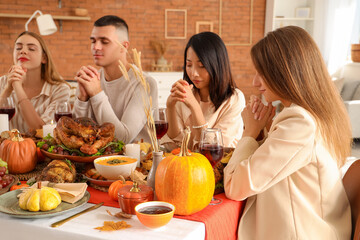 Sticker - Group of young friends praying before dinner at festive table on Thanksgiving Day