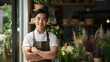 Confident young Asian male florist smiling on blurred flower shop background, owner of small business of a flower shop, with copy space.