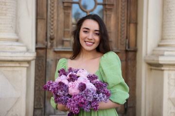 Canvas Print - Beautiful woman with bouquet of spring flowers near building outdoors