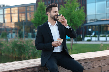 Poster - Smiling young businessman having his lunch outdoors