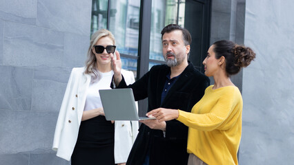 Group of business people talking and discussing strategy, business brochure, working together using laptops outside outdoor office