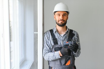 Wall Mural - Workman in overalls installing or adjusting plastic windows in the living room at home