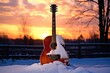 wintery sunset behind a snow covered acoustic guitar on stand