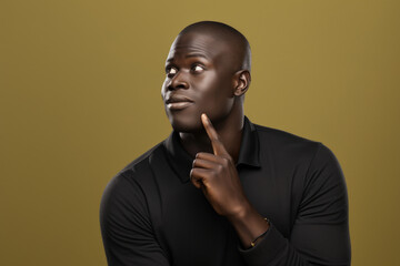 Poster - A man wearing a black shirt is captured in this image as he holds his finger to his face. This picture can be used to portray thoughtfulness, contemplation, or secrecy in various contexts.