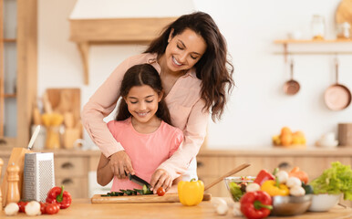 Mom Teaching Kid Girl To Cook Cutting Vegetables At Kitchen