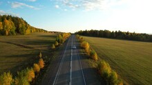 One White Car Driving On An Asphalt Road In The Autumn Season, Aerial View. Colorful Trees. Picturesque Autumn Landscapes During Sunset. 