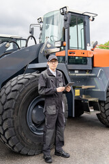 Poster - Serviceman with digital tablet on a background of the tractor.