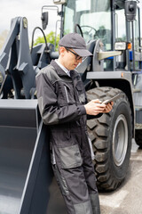 Poster - Serviceman with digital tablet on a background of the tractor.